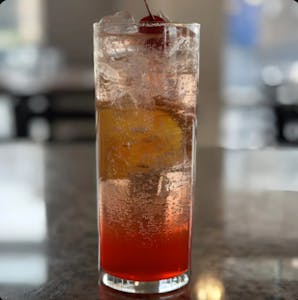 Tall fizzy drink in a highball glass with a cherry and orange slice