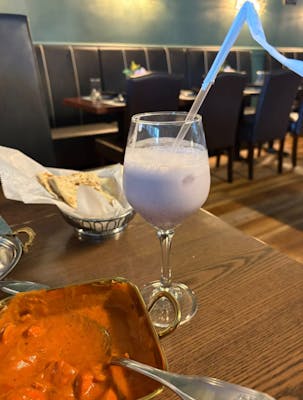 Sweet Lassi with curry and naan in background