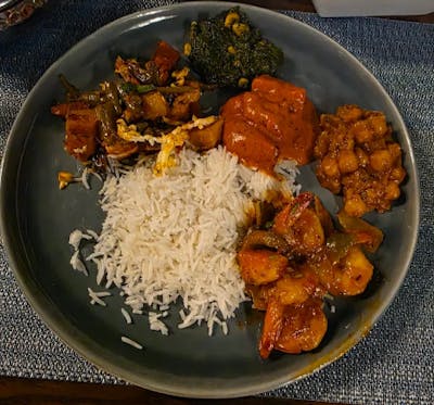 Basmati rice plate with saag, chicken/paneer tikka masala, chana masala, shrimp curry, and veg jalfrezi-style stir-fry.