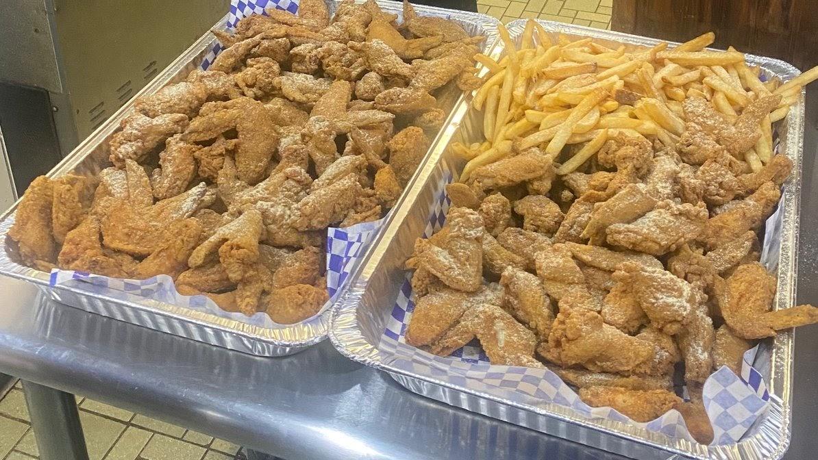 Catering trays of fried chicken wings and fries