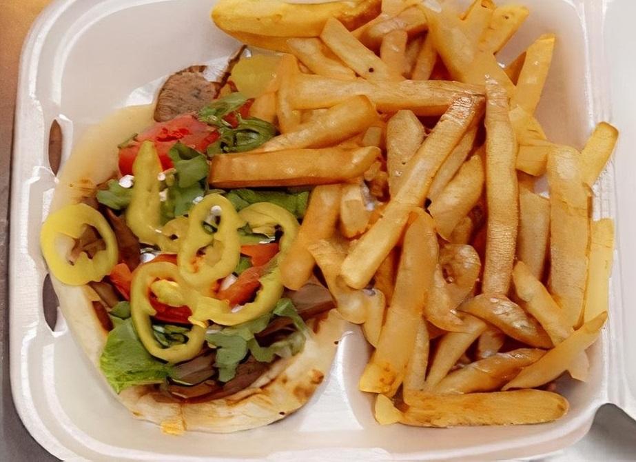 Gyro pita with banana peppers and fries in a takeout box