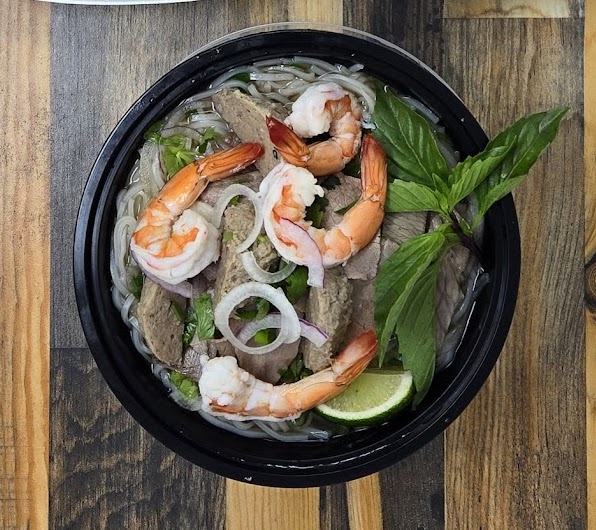 flat rice noodles in a rich, aromatic broth, topped with ingredients such as tender meat, shrimp, and fresh herbs