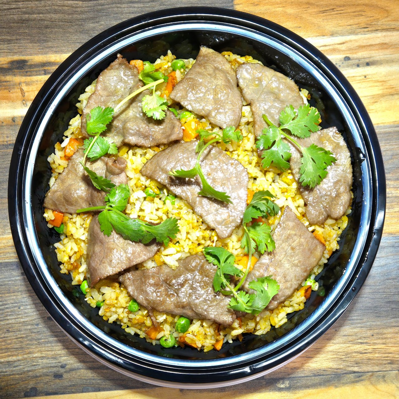 slices of beef served over a bed of fried rice