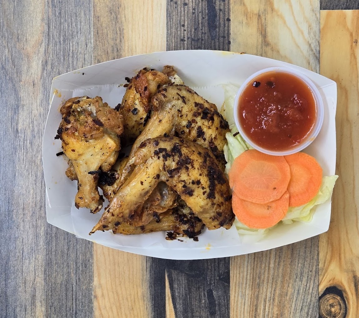 grilled or roasted chicken wings served with a dipping sauce and vegetable garnish