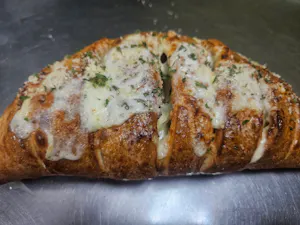Golden-brown calzone topped with melted cheese, garlic, and herbs