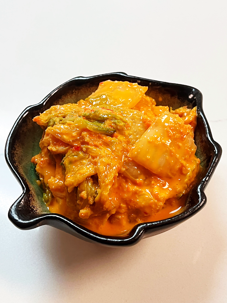 Spicy fermented cabbage in chili sauce served in a black bowl