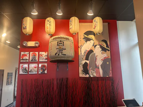 Red accent wall with Japanese lanterns, a decorative sake barrel, and classic artwork inside Sushirito Restaurant in Loveland, CO